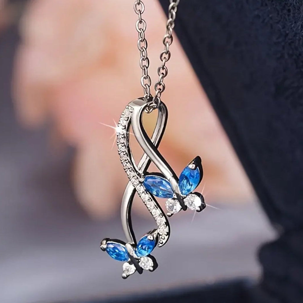 Necklace with butterfly pendant featuring blue gemstones on a blurred background