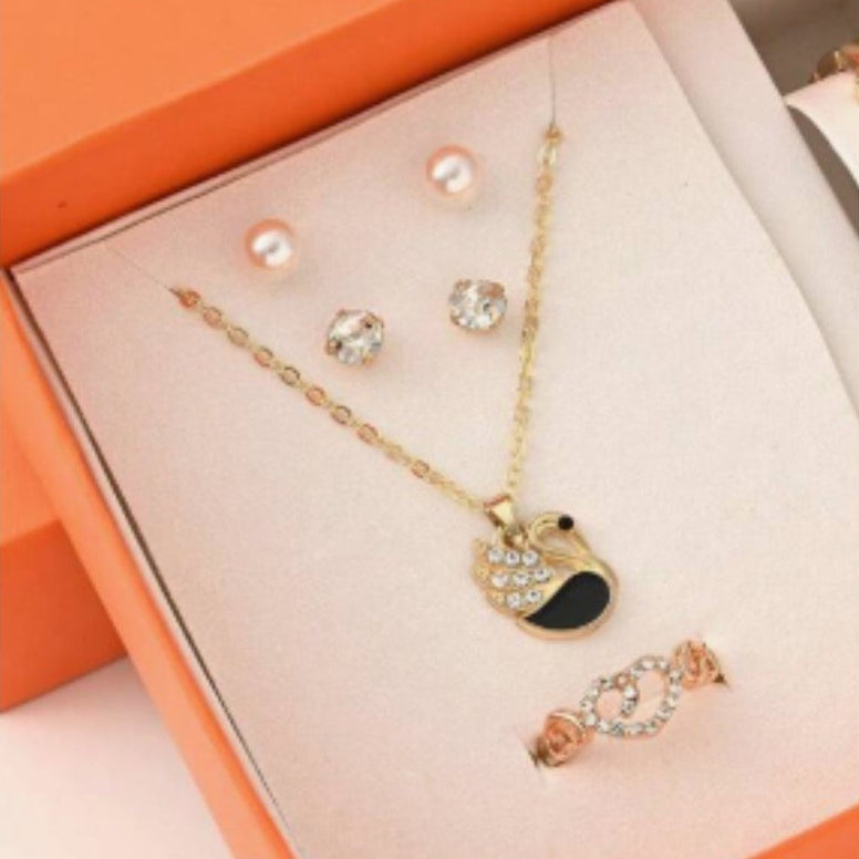 Jewelry set with necklace, earrings, and bracelet on a pink cushion in an orange box.