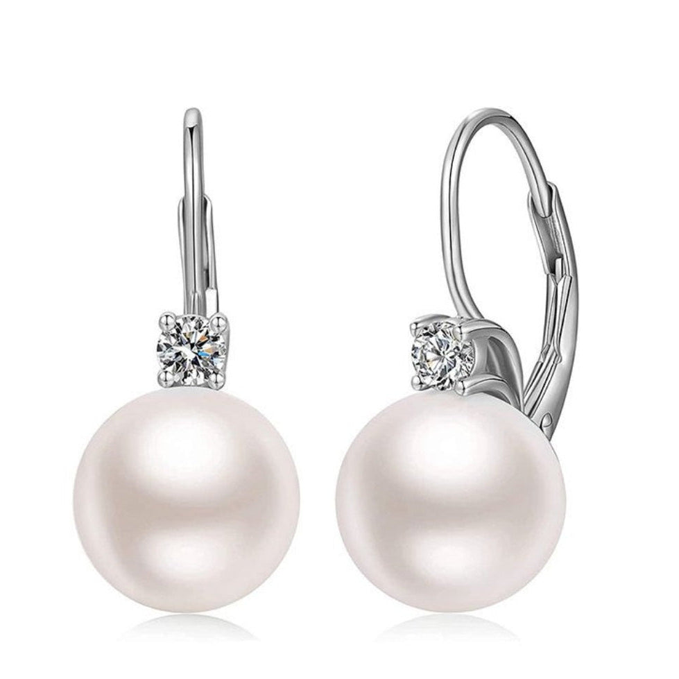 Pearl earrings with silver hooks and clear gemstones on a white background