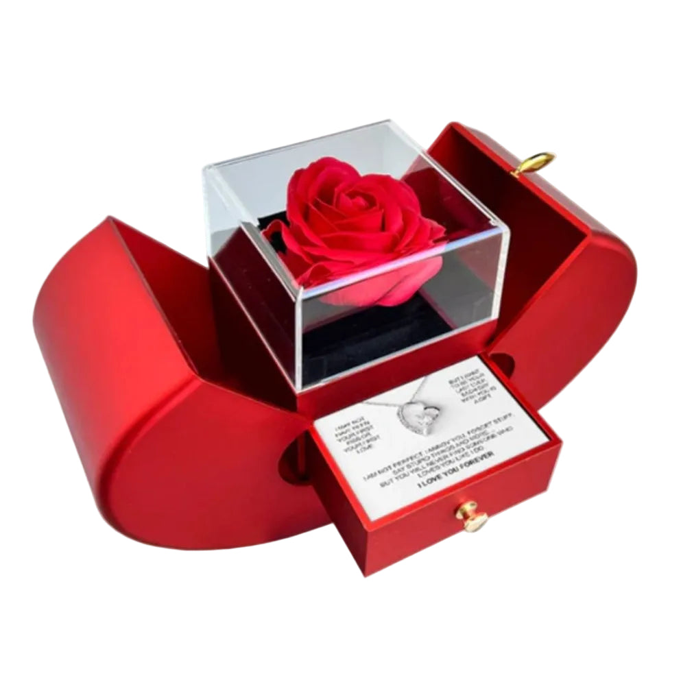 Red rose in a transparent cube within an open red box, accompanied by a card and necklace.